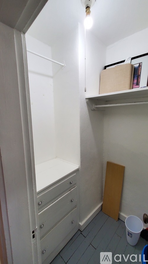 A small, empty room with a white door and a shelf with a box on it.