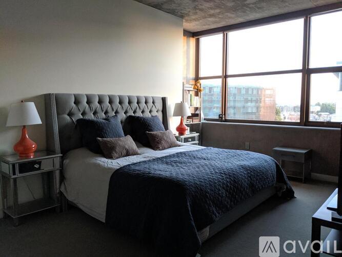 A bedroom with a large bed and a window overlooking a cityscape.