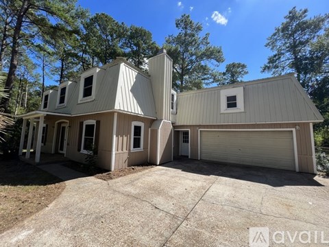 A modern house with a large garage is situated in a wooded area.