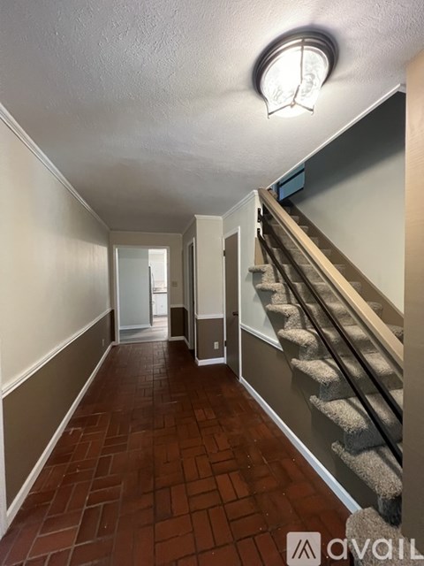 A hallway with a staircase on the right and a door on the left.