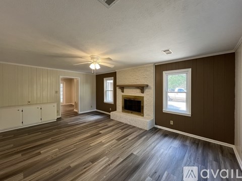A spacious room with wood flooring and a fireplace.