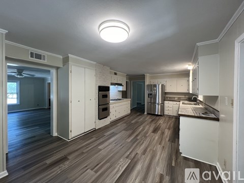 A kitchen with wooden floors and white cabinets.