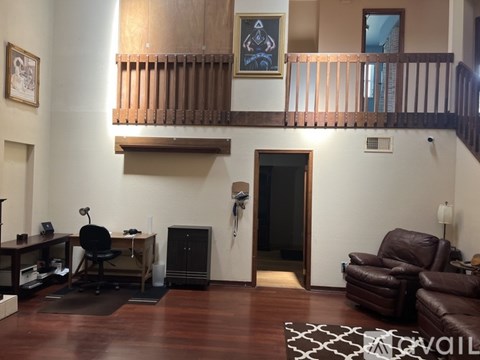 A living room with a brown leather couch and a black chair.
