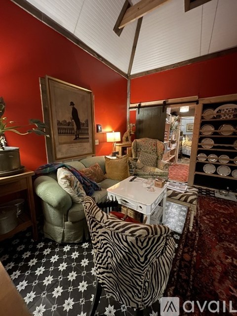 A living room with a zebra print chair and a painting of a man on the wall.