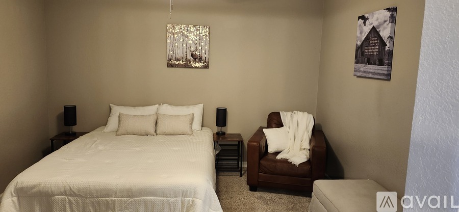 A bedroom with a white bed and a brown chair.