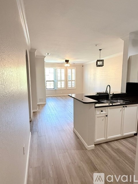 A kitchen with white cabinets and a black countertop.
