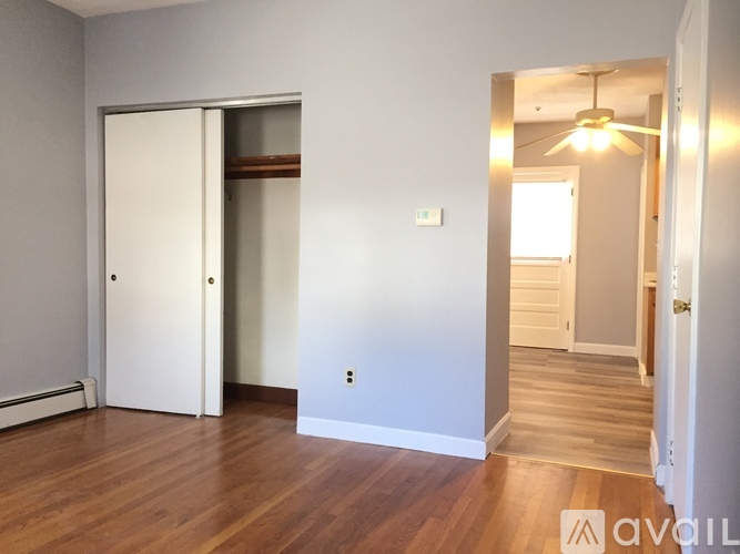 A room with a white door and wooden floors.