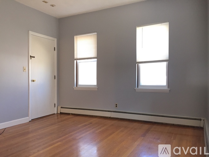 A room with wooden floors and two windows.