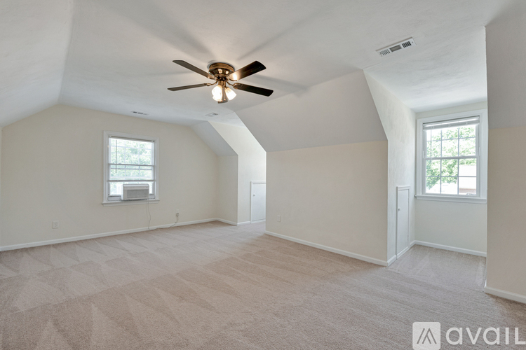 A spacious room with a ceiling fan and carpeted floor.