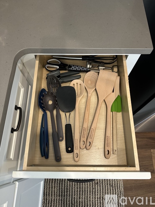 A drawer full of utensils including scissors, spoons, and spatulas.