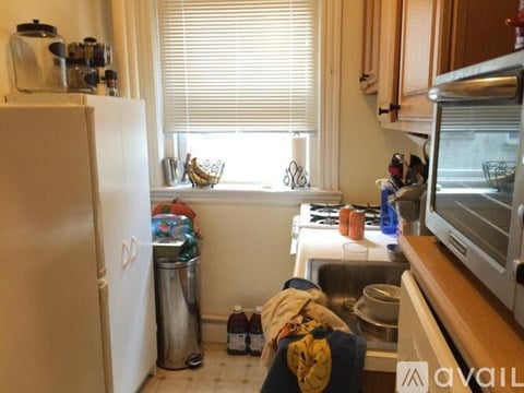 A kitchen with a white fridge, a window with blinds, a sink, and a microwave.