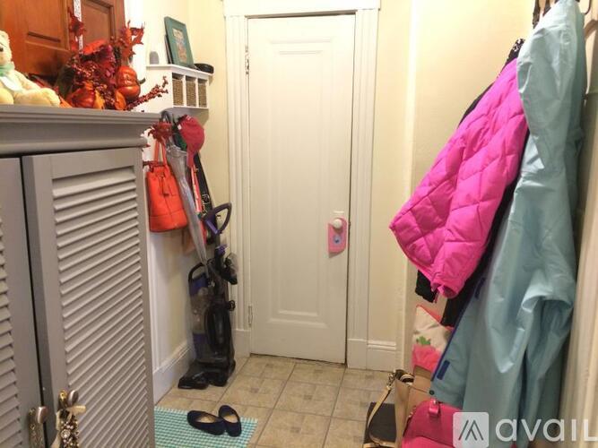 A hallway with a door and a pair of shoes on the mat.