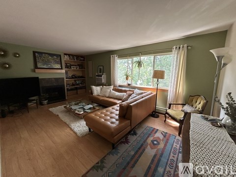 A living room with a brown leather couch and a fireplace.