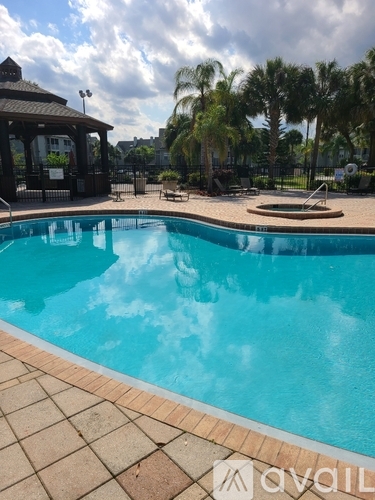A pool with a pavilion and palm trees in the background.
