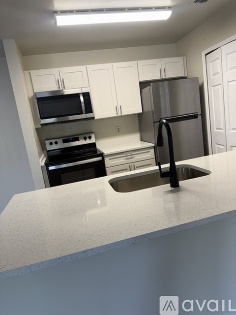 A kitchen with white cabinets and a stainless steel refrigerator.