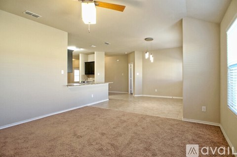 A spacious room with a carpeted floor and a ceiling fan.
