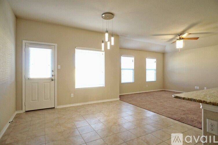 A room with a rug, a ceiling fan, and a door.