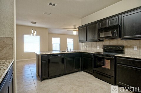 A kitchen with black appliances and a tiled floor.