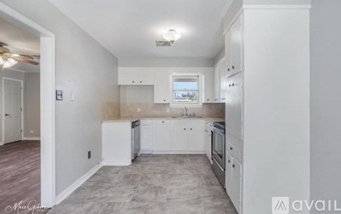 A kitchen with white cabinets and a window above the sink.