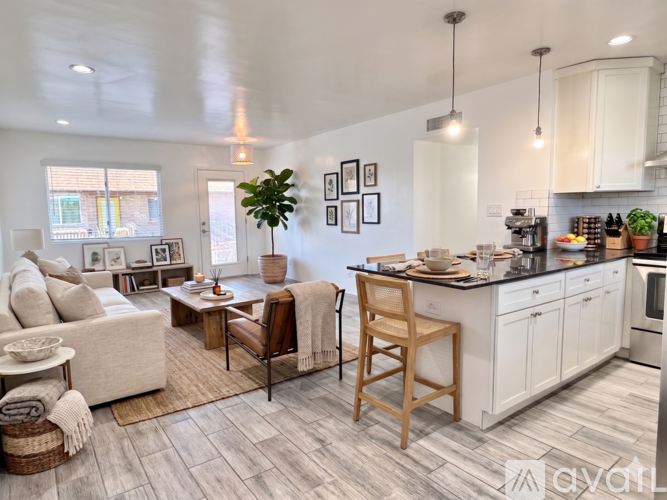 A well-lit kitchen and living room with a dining table and chairs.