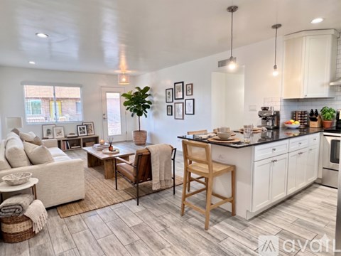 A well-lit kitchen and living room with a dining table and chairs.