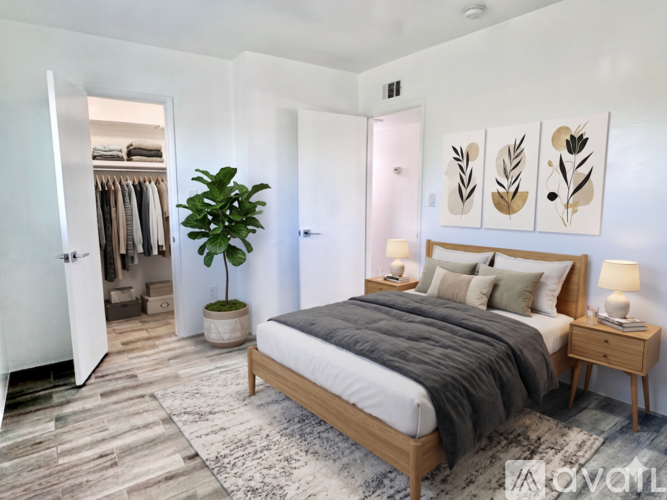 A bedroom with a large bed and a plant in a pot.