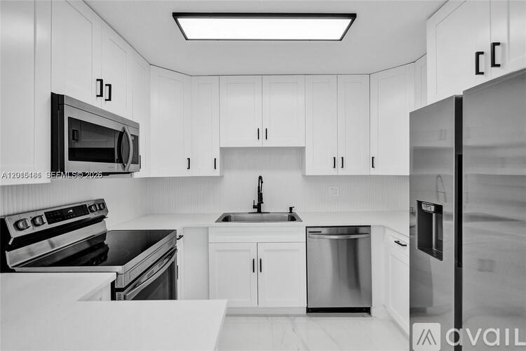 A modern kitchen with white cabinets and stainless steel appliances.