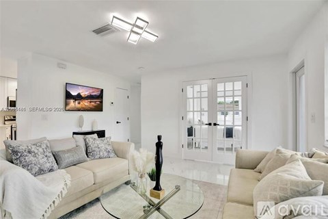 A modern living room with a glass coffee table and a large painting on the wall.