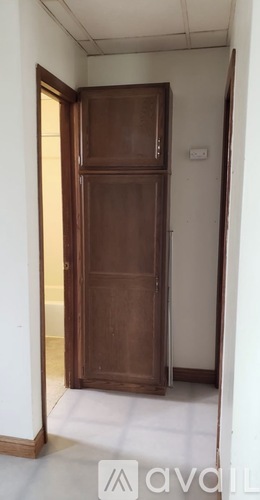 A brown wardrobe stands in a white room.