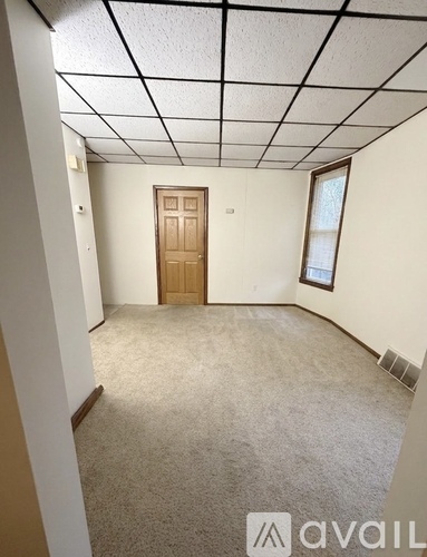A room with a carpeted floor, a door, and a window.