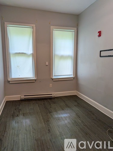 A room with two windows and a fire extinguisher on the wall.