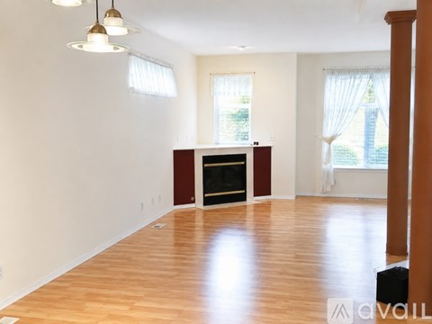 A living room with a fireplace and wooden floors.