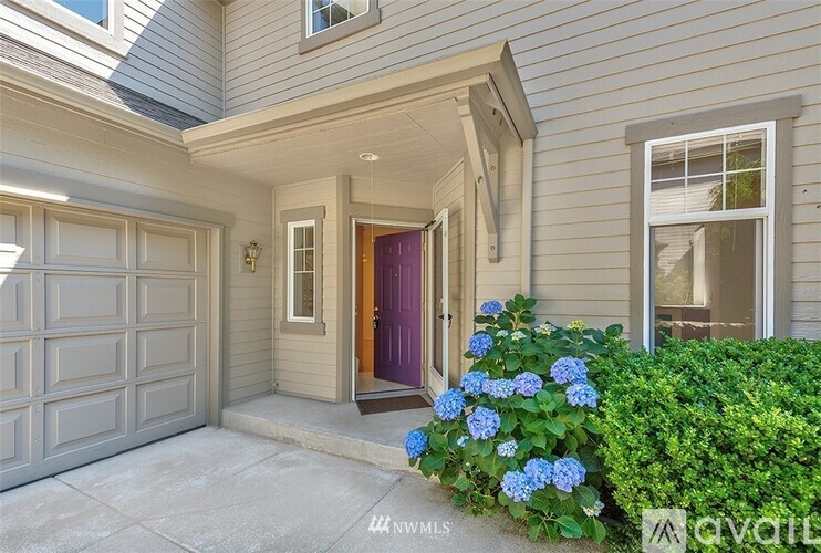 A house with a purple door and a window with a view of a tree.