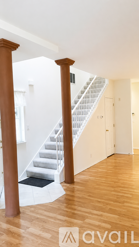 A staircase with a wooden handrail and a black mat on the floor.
