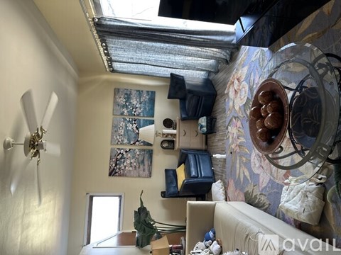 A room with a ceiling fan and a wall with a painting on it.