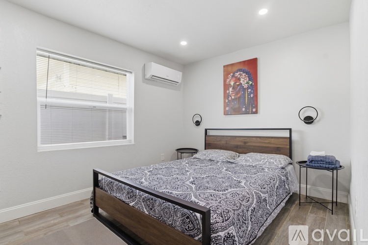 A bedroom with a bed, nightstand, and window.