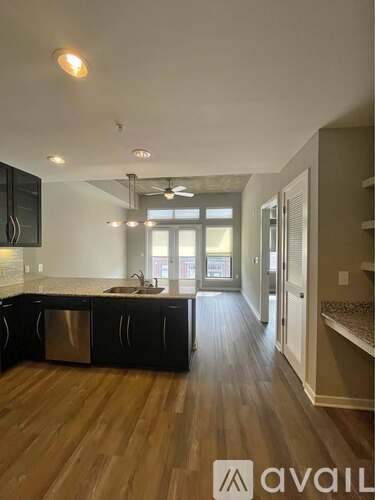 A kitchen with black cabinets and a wooden floor.