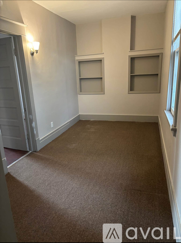 A room with a carpeted floor and a door on the left.