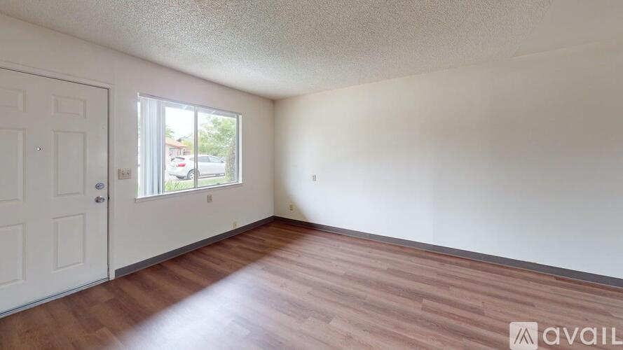 A room with wooden flooring and a door leading to a balcony.