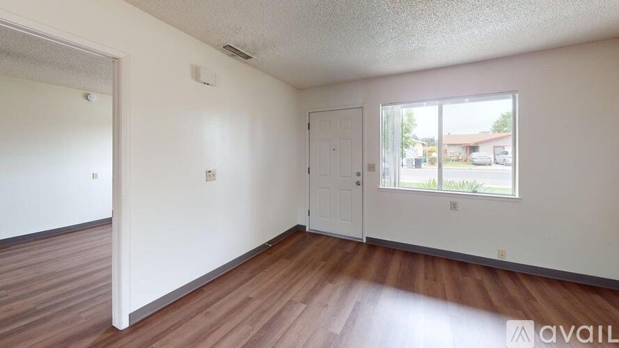 A room with wooden floors and white walls is available for rent.
