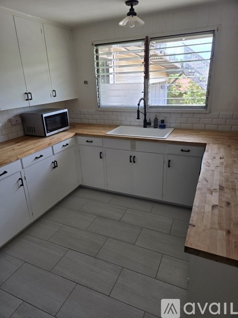 A kitchen with white cabinets and a wooden countertop.