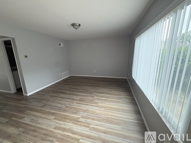 A room with wooden flooring and a window with blinds.