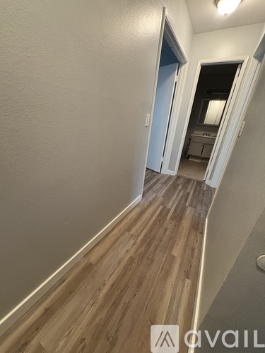 A hallway with wood flooring and a door on the left.