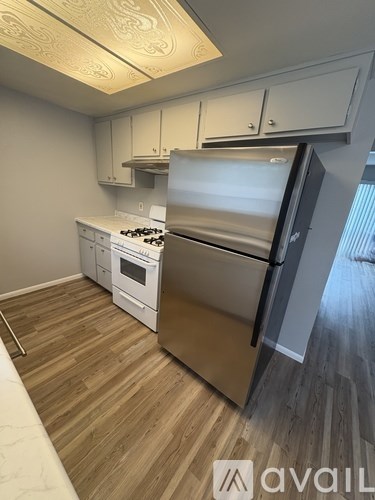 A kitchen with a stainless steel refrigerator and a white stove top oven.