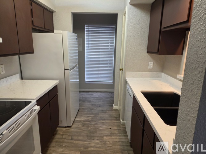 A kitchen with brown cabinets and a white fridge.