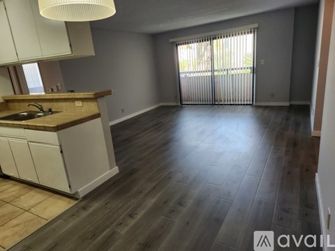 A kitchen with a wooden floor and white cabinets is available for rent.
