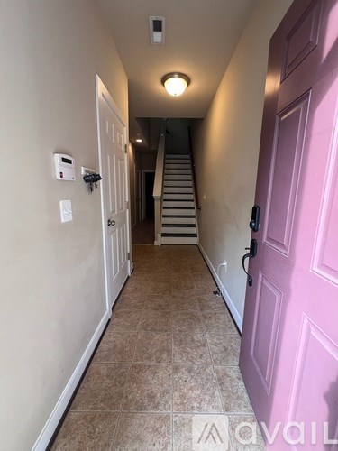 A hallway with a pink door and a staircase.