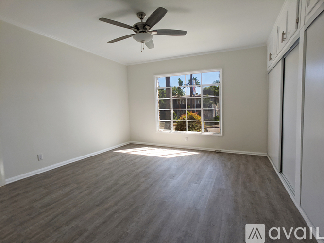 A room with a ceiling fan and a window overlooking a building.