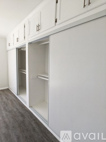 A kitchen with white cabinets and a grey floor.