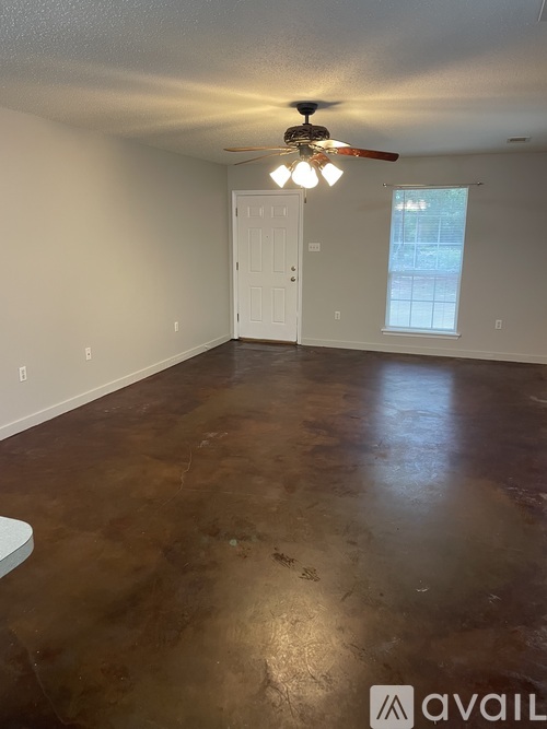 A room with a ceiling fan and brown flooring.